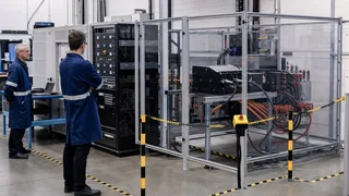 Engineers reviewing a guarded regenerative AC and DC power electronics test bench